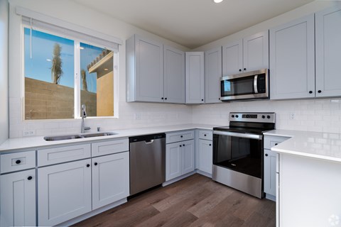 a kitchen with gray cabinets and stainless steel appliances